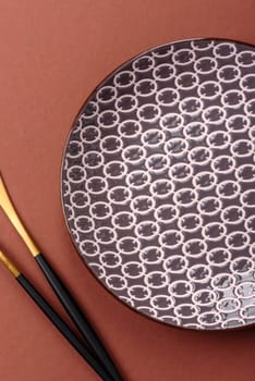 Empty ceramic plate on a monochrome brown background. Empty plate with cutlery on a dining table