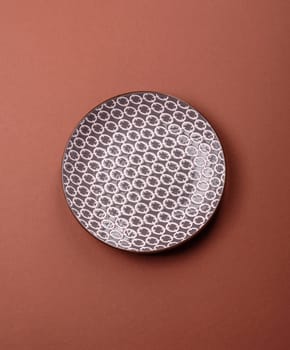 Empty ceramic plate on a monochrome brown background. Empty plate with cutlery on a dining table