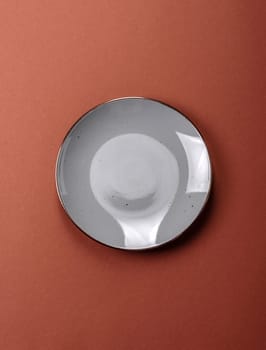 Empty ceramic plate on a monochrome brown background. Empty plate with cutlery on a dining table