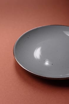 Empty ceramic plate on a monochrome brown background. Empty plate with cutlery on a dining table