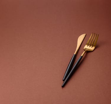 Knife and fork, cutlery on a brown dining table. Utensils and crockery for preparing dinner