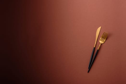 Knife and fork, cutlery on a brown dining table. Utensils and crockery for preparing dinner