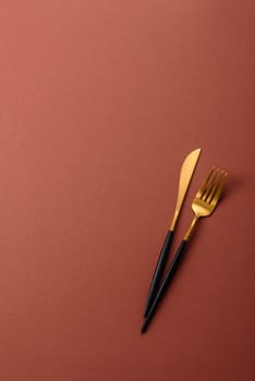 Knife and fork, cutlery on a brown dining table. Utensils and crockery for preparing dinner