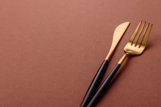 Knife and fork, cutlery on a brown dining table. Utensils and crockery for preparing dinner