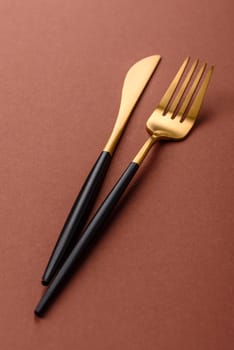 Knife and fork, cutlery on a brown dining table. Utensils and crockery for preparing dinner