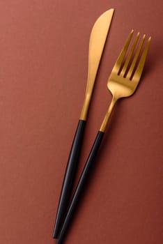 Knife and fork, cutlery on a brown dining table. Utensils and crockery for preparing dinner