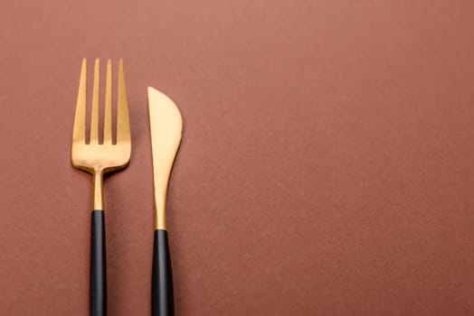 Knife and fork, cutlery on a brown dining table. Utensils and crockery for preparing dinner