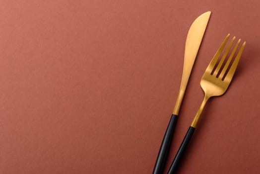 Knife and fork, cutlery on a brown dining table. Utensils and crockery for preparing dinner