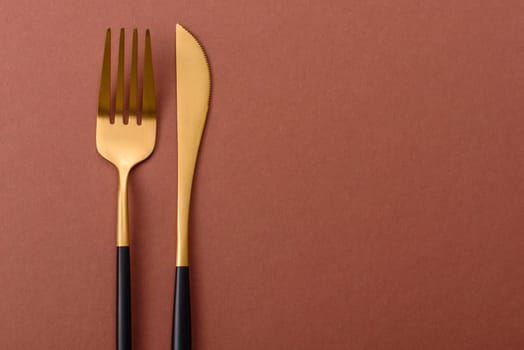 Knife and fork, cutlery on a brown dining table. Utensils and crockery for preparing dinner