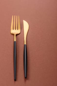 Knife and fork, cutlery on a brown dining table. Utensils and crockery for preparing dinner