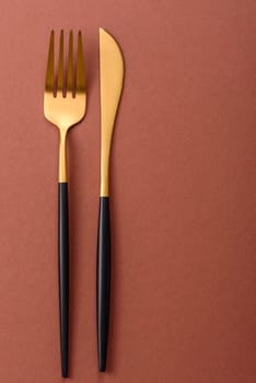 Knife and fork, cutlery on a brown dining table. Utensils and crockery for preparing dinner