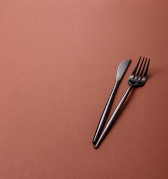 Knife and fork, cutlery on a brown dining table. Utensils and crockery for preparing dinner