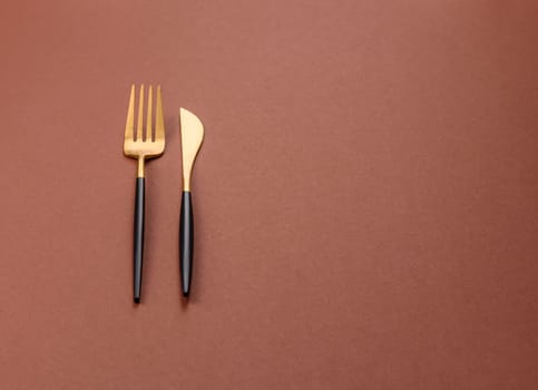 Knife and fork, cutlery on a brown dining table. Utensils and crockery for preparing dinner