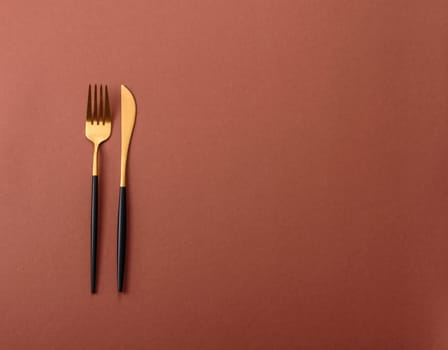 Knife and fork, cutlery on a brown dining table. Utensils and crockery for preparing dinner