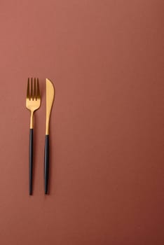 Knife and fork, cutlery on a brown dining table. Utensils and crockery for preparing dinner
