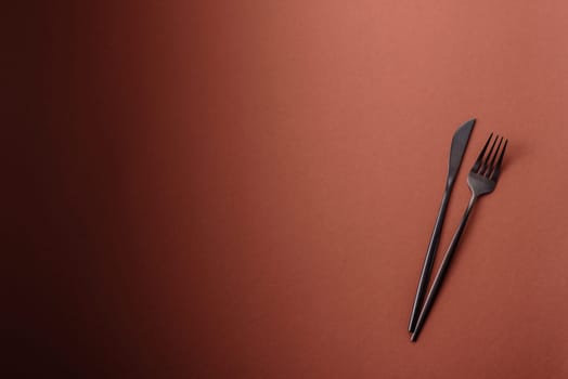 Knife and fork, cutlery on a brown dining table. Utensils and crockery for preparing dinner