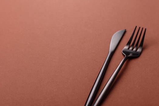 Knife and fork, cutlery on a brown dining table. Utensils and crockery for preparing dinner