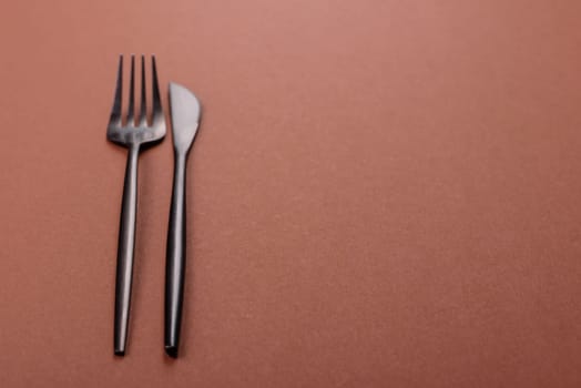 Knife and fork, cutlery on a brown dining table. Utensils and crockery for preparing dinner