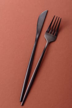 Knife and fork, cutlery on a brown dining table. Utensils and crockery for preparing dinner