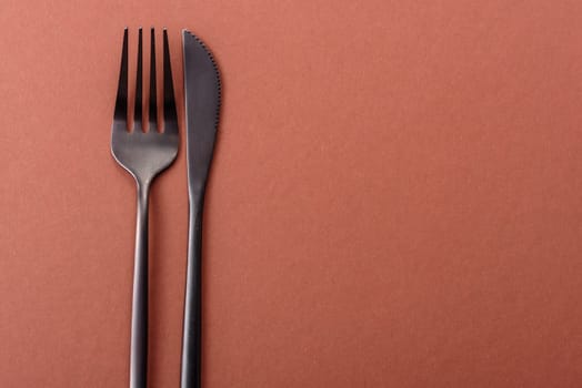 Knife and fork, cutlery on a brown dining table. Utensils and crockery for preparing dinner
