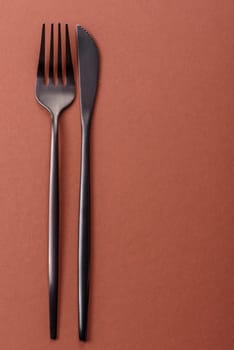 Knife and fork, cutlery on a brown dining table. Utensils and crockery for preparing dinner