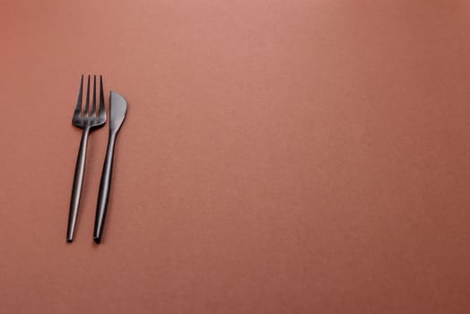 Knife and fork, cutlery on a brown dining table. Utensils and crockery for preparing dinner