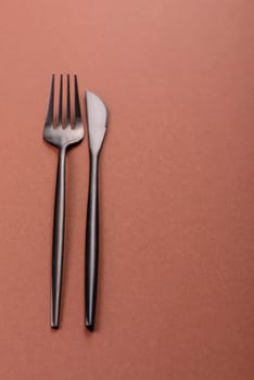 Knife and fork, cutlery on a brown dining table. Utensils and crockery for preparing dinner