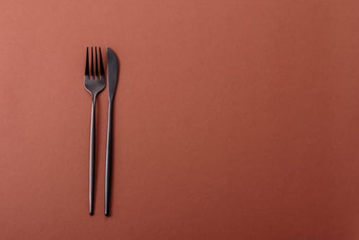 Knife and fork, cutlery on a brown dining table. Utensils and crockery for preparing dinner