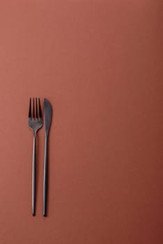 Knife and fork, cutlery on a brown dining table. Utensils and crockery for preparing dinner