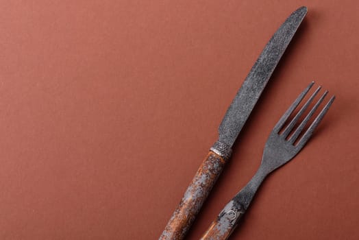 Knife and fork, cutlery on a brown dining table. Utensils and crockery for preparing dinner