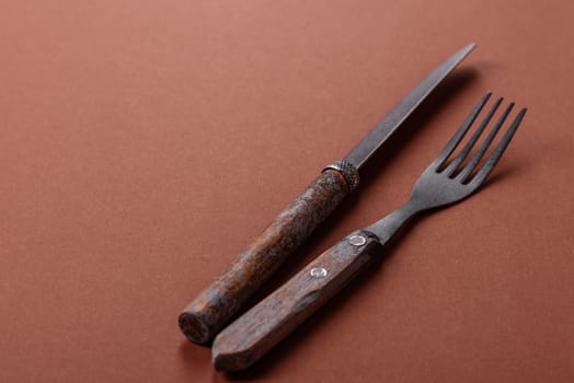Knife and fork, cutlery on a brown dining table. Utensils and crockery for preparing dinner