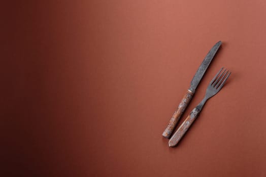 Knife and fork, cutlery on a brown dining table. Utensils and crockery for preparing dinner