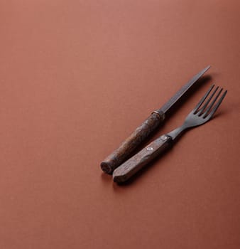 Knife and fork, cutlery on a brown dining table. Utensils and crockery for preparing dinner