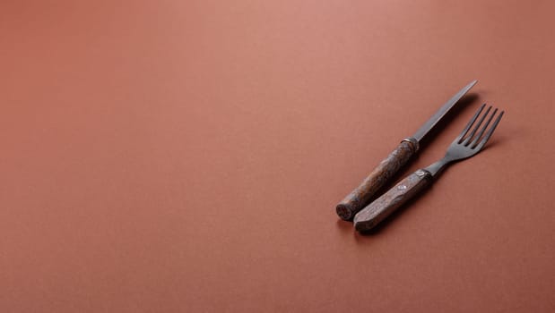 Knife and fork, cutlery on a brown dining table. Utensils and crockery for preparing dinner