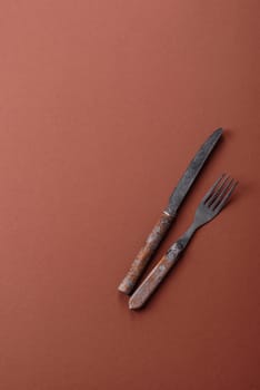 Knife and fork, cutlery on a brown dining table. Utensils and crockery for preparing dinner