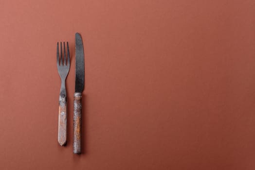 Knife and fork, cutlery on a brown dining table. Utensils and crockery for preparing dinner