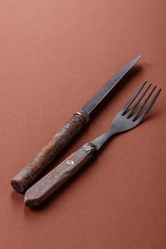 Knife and fork, cutlery on a brown dining table. Utensils and crockery for preparing dinner