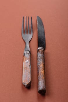 Knife and fork, cutlery on a brown dining table. Utensils and crockery for preparing dinner