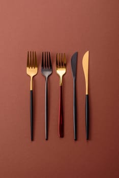 Knife and fork, cutlery on a brown dining table. Utensils and crockery for preparing dinner