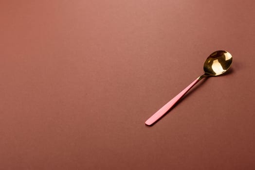 Empty metal spoon on a monochrome brown background. Cutlery on the dining table
