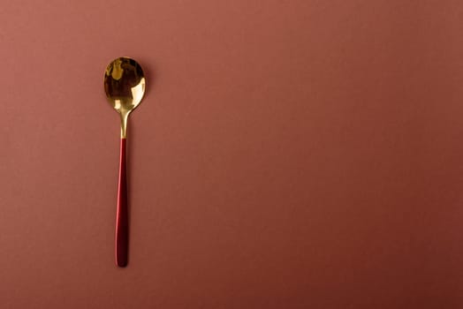 Empty metal spoon on a monochrome brown background. Cutlery on the dining table