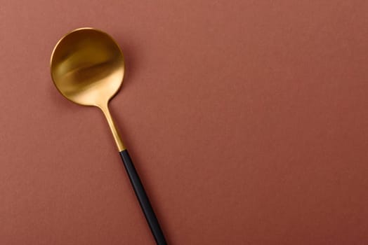 Empty metal spoon on a monochrome brown background. Cutlery on the dining table