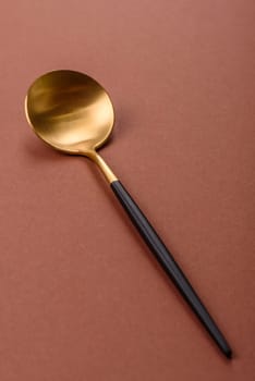 Empty metal spoon on a monochrome brown background. Cutlery on the dining table