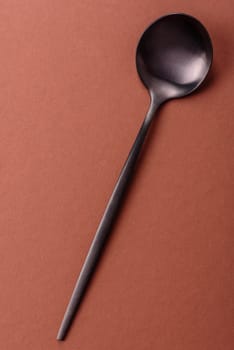 Empty metal spoon on a monochrome brown background. Cutlery on the dining table