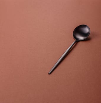 Empty metal spoon on a monochrome brown background. Cutlery on the dining table