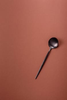 Empty metal spoon on a monochrome brown background. Cutlery on the dining table