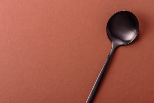 Empty metal spoon on a monochrome brown background. Cutlery on the dining table