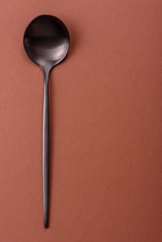 Empty metal spoon on a monochrome brown background. Cutlery on the dining table