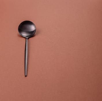 Empty metal spoon on a monochrome brown background. Cutlery on the dining table