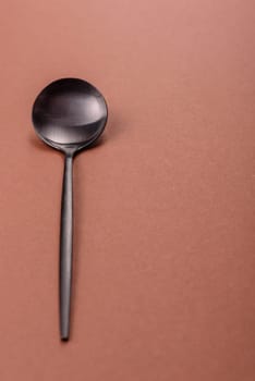 Empty metal spoon on a monochrome brown background. Cutlery on the dining table
